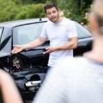 Male and female drivers arguing over damage to cars after an accident