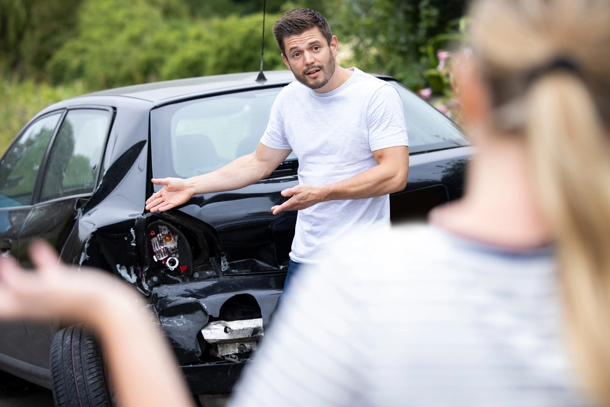 Male and female drivers arguing over damage to cars after an accident
