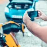 Man using his phone to photograph damage after a motorcycle accident